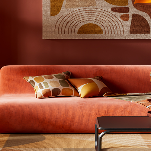 Retro-styled living room with a burnt orange velvet sofa, patterned cushions and throw blanket, a rounded rattan-shade floor lamp, dark wood shelving, and an abstract arch-patterned wall art above the sofa.