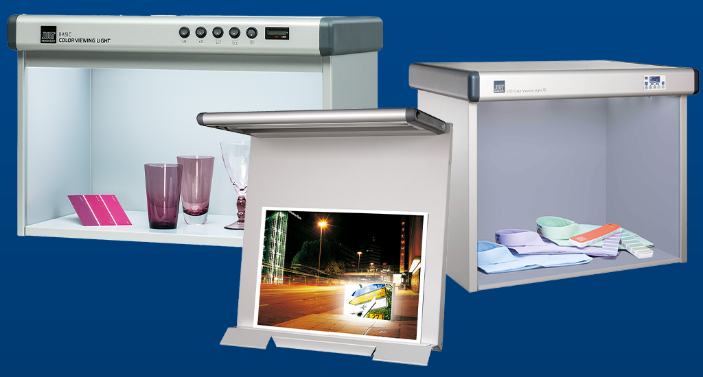 Banner showing three JUST Normlicht viewing booths for colour evaluation on a blue background, with colour guides being used to evaluate colours on photographic prints, products and textiles under standardised lighting