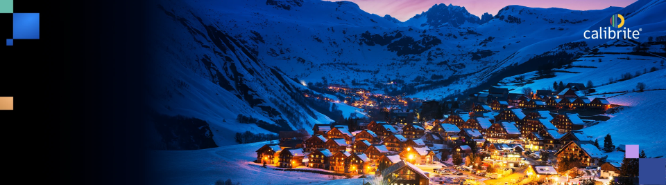 Snowy mountain village at night with illuminated buildings and Calibrite logo.
