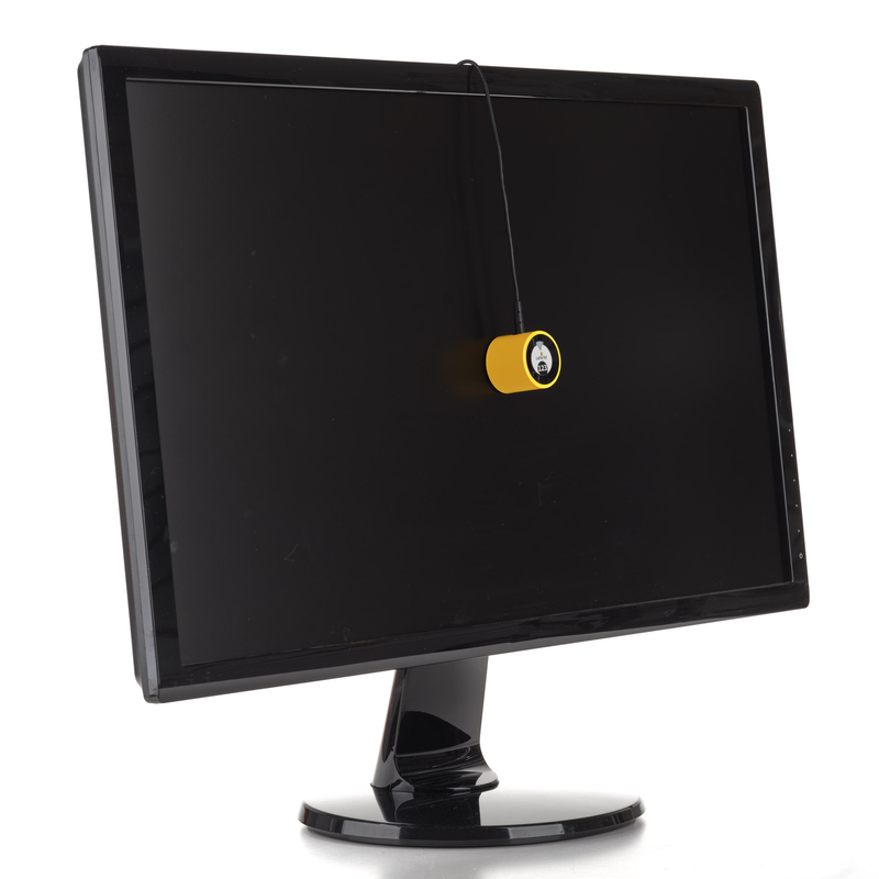 An image showing the Calibrite Display 123, device for calibrating the colour on your monitor, hung by its cable over a monitor screen so that the sensor is against the screen for measuring the screen colour during calibration.