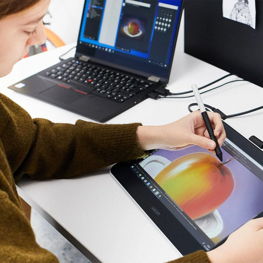 An illustrator working at a desk, drawing with a Wacom One Creative Pen Display Graphics Tablet.