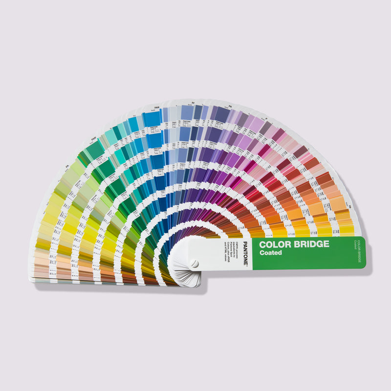 Fanned out PANTONE Color Bridge guidebooks - essential tools for precise colour matching in design and printing. The guides feature an array of colour swatches showcasing a diverse spectrum, accompanied by values for PANTONE spot colours and their nearest matches in CMYK, RGB, and HEX color codes. These guides aid designers and printers in achieving consistent and accurate colour representation across different mediums.